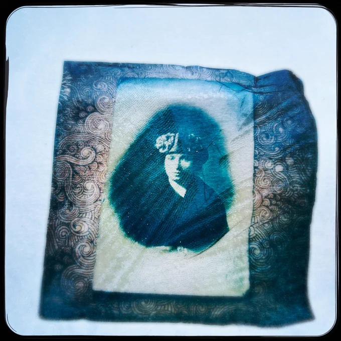 Portrait ancien et diffus d’une femme, imprimé en teintes bleu-vert sur papier texturé, entouré d’un motif ornemental ; plis et micro-fissures visibles.
