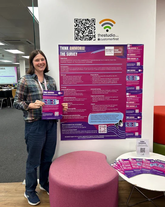 Community member smiling stood next to our large A0 poster sharing the results of our hyperammonaemia survey. 