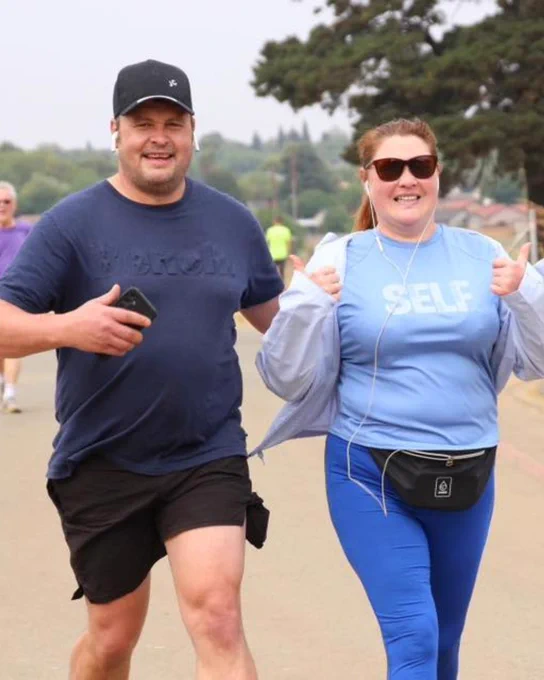 Two parkrunners running and giving thumbs up.