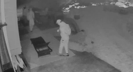 Surveillance photo showing two people in hoodies and masks walking 