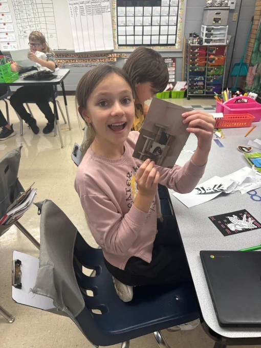 middle schooler with a pink shirt and long brown hair in a ponytail holds a picture of a cat