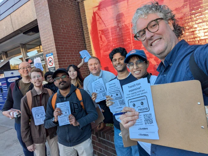 group of people holding flyers standing in front of a subway entrance