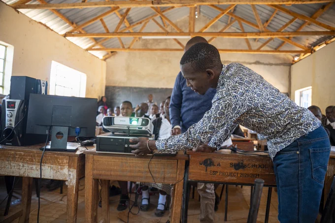 A teacher in Ukala, Kenya is setting up a projector for class for the first time.