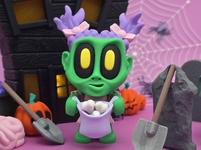 Close-up of the 3D-printed Zombie Girl figure with purple hair, pink bows, and a pastel bucket of white bones, posed in a Halloween graveyard scene.