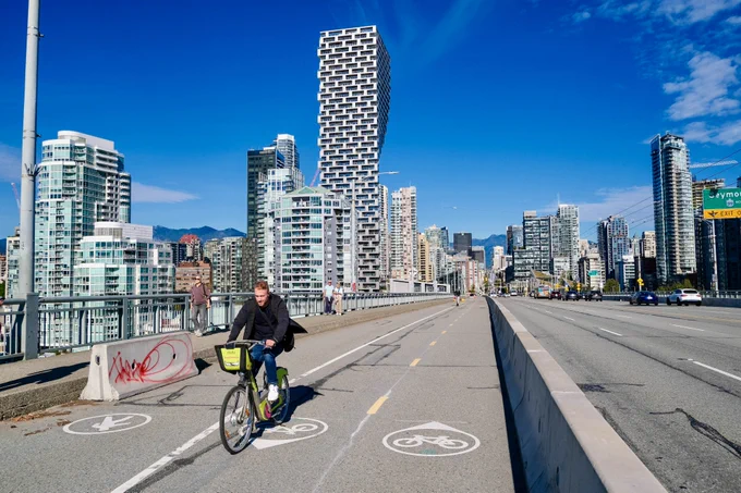 People of all ages and abilities ride bicycles on protected cycling infrastructure on the streets of Downtown Vancouver.