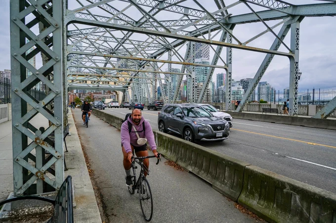 People of all ages and abilities ride bicycles on protected cycling infrastructure on the streets of Downtown Vancouver.