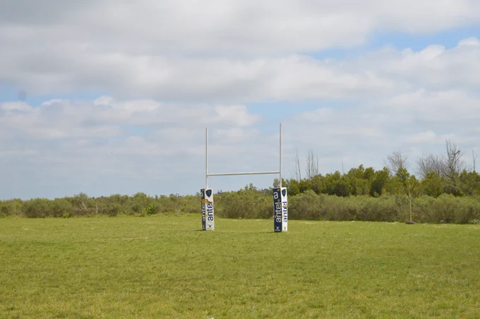 cancha de rugby, pasto verde y vista del cielo y las nubes.