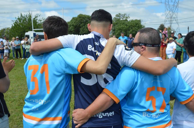 Dos jugadores de totem xv abrazan a uno de halcones en la ronda final del partido.