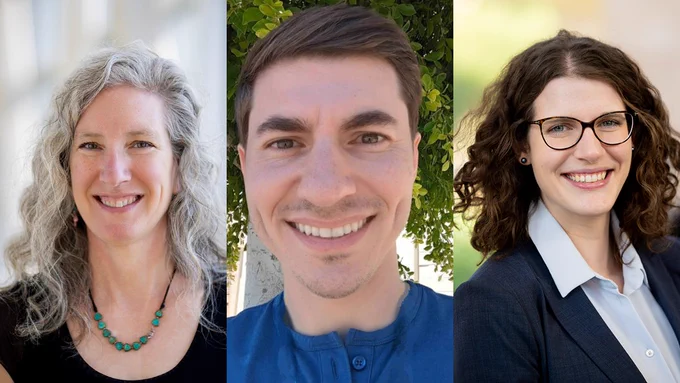 Three smiling professionals posing for a portrait, from left to right: a person with shoulder-length curly hair wearing a turquoise necklace, a person in a blue shirt, and a person in a dark blazer with curly hair and glasses.