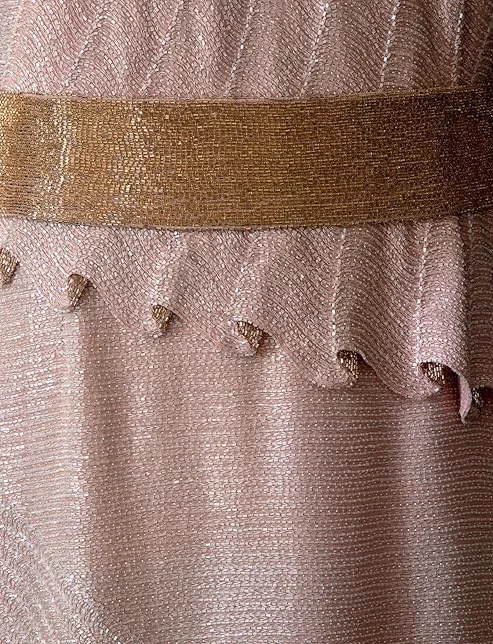Beaded detail of a pink 1930s evening dress by Jean Patou. The photograph focuses on the gold beaded belt and the illusion of pleats