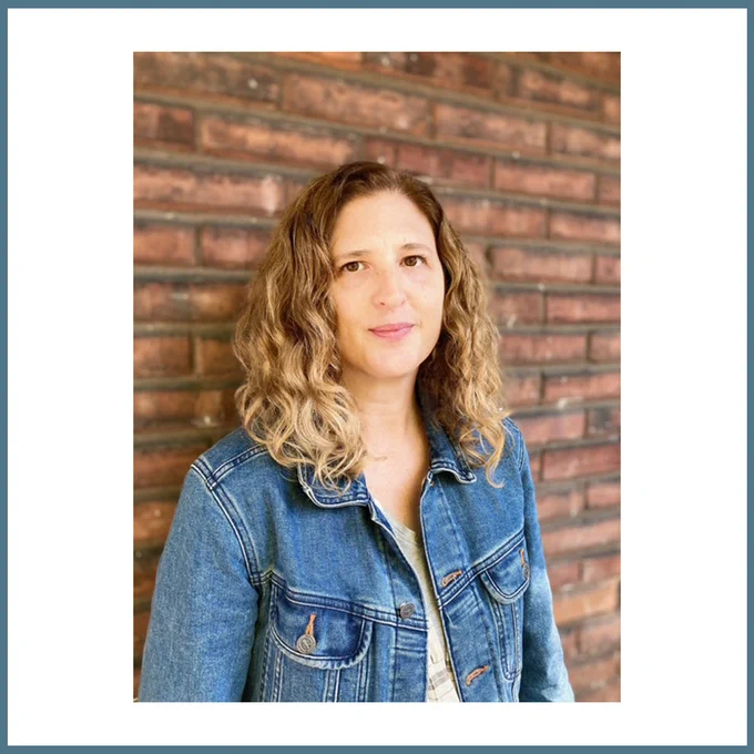 The post has a white background and is framed by a teal border. Centred is an image of V.M. Ellis standing against a brick wall, wearing a denim jacket and smiling directly at the camera. 
