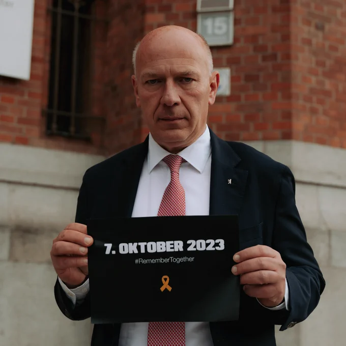 Kai Wegner mit dem Schild #RememberTogether in den Händen.