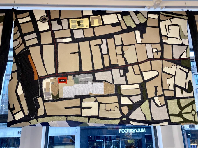 This is the central panel of the tapestry of pre-loved clothing made in a collaboration between Uniqlo and Govanhill Baths Community Trust. The panels has been hand stitched into an abstracted map of Glasgow’s city centre with key details such as George Square, the St Enoch Centre and Glasgow Central Station picked out in different types and patterns of cloth with the Uniqlo store highlighted in red.