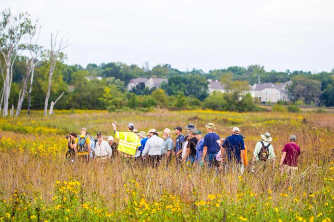 A group of people walking down the prairie at Deer Grove East.