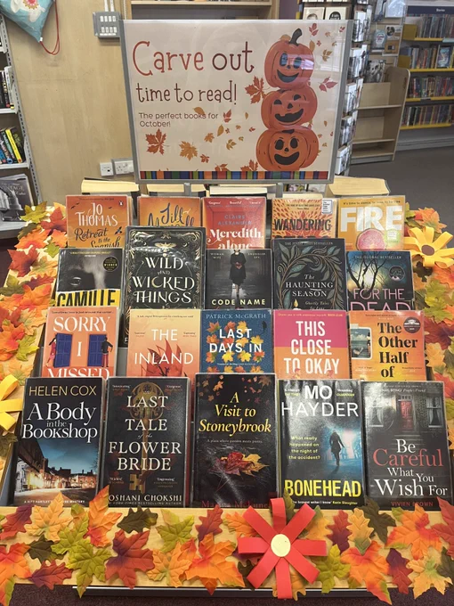 An autumnal book display at Oxted Library entitled 'Carve out time to read'. There are fake autumn leaves decorating it.