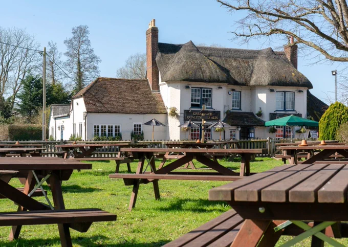 thatched country pub surrounded by wooden benches