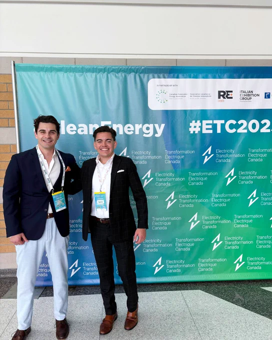 Two Silfab Solar team members smiling and posing in front of a banner for "Clean Energy #ETC2022" at a public event. Both are wearing lanyards and professional attire.