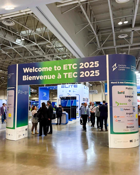 Entrance to the ETC 2025 conference with welcome banners in English and French, people milling around exhibit booths representing various energy companies.