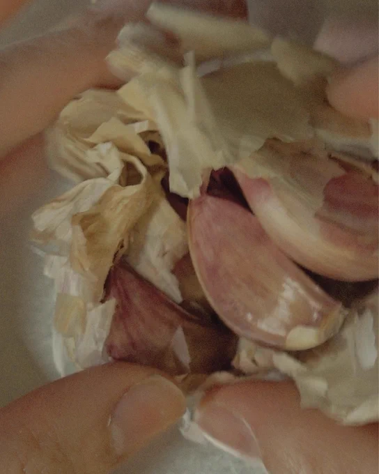 Hands peeling cloves of garlic.