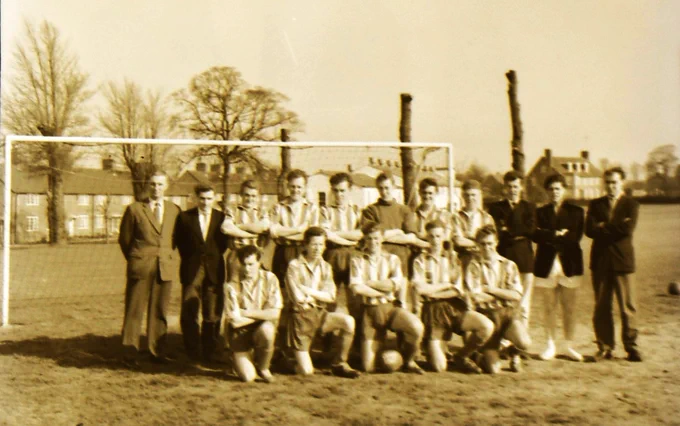 Black and white photograph of a football team in front of a goalpost.
