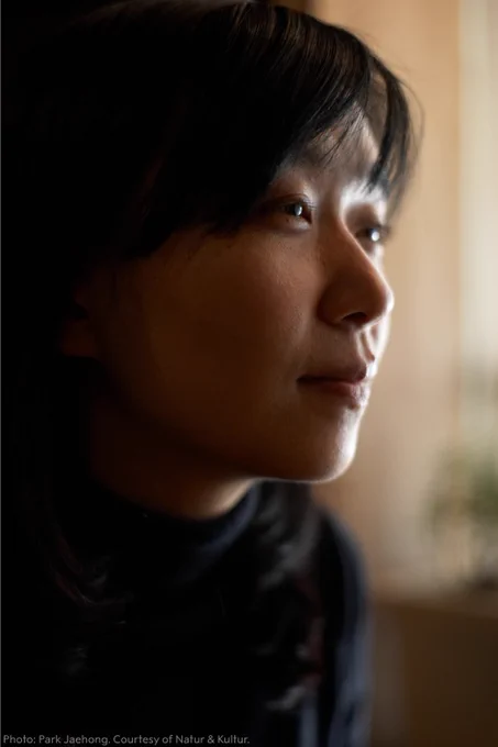Close-up portrait of Han Kang looking to the side, with soft lighting emphasising a thoughtful expression. 