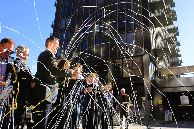 An image of St. Louis city leaders and developers celebrating the groundbreaking of the Mansion House redevelopment with streamers, with the Mansion House in the background.
