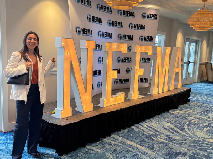 Bytes.co Sales Manager Abby Turner standing and smiling next to the NEFMA sign