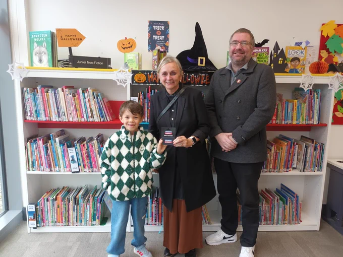 Photo of Sam with Cllr Feeley and Cllr Mills in Droylsden Library. Sam is holding his voucher. 