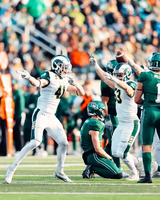 University of Regina Rams linebackers Liam LaBelle and Owen Zimmer celebrate after a play while pointing to their right as an opposing University of Saskatchewan Huskies player kneels on the ground during a U Sports football game.