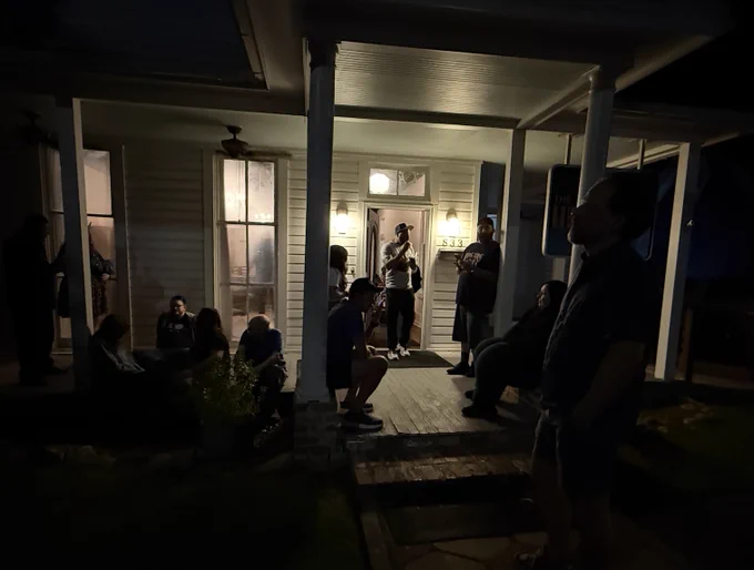 a night photo with all the speakers hanging out on a porch