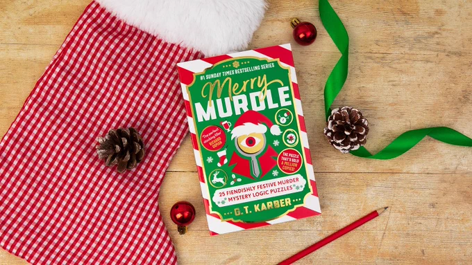 A flat lay photograph of the book Merry Murdle by GT Karber, surrounded by Christmassy objects including a Christmas stocking, baubles, ribbon and pine cones.