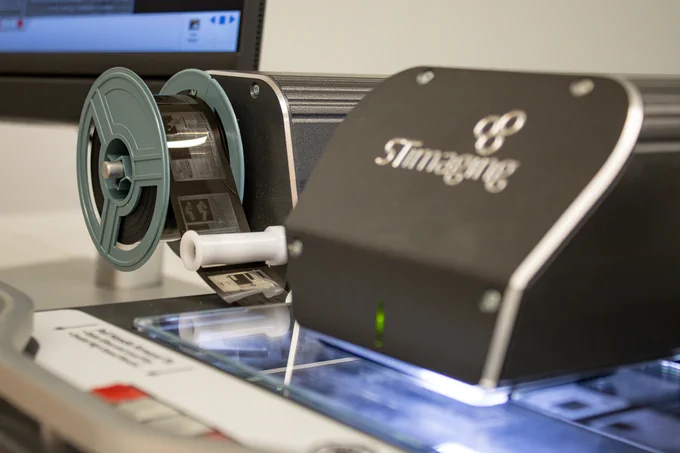 Spools of microfilm depicting pages of newspapers run through a scanning device