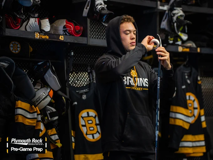 Bruins defenseman Jordan Harris tapes his stick in front of his stall in the B's dressing room.