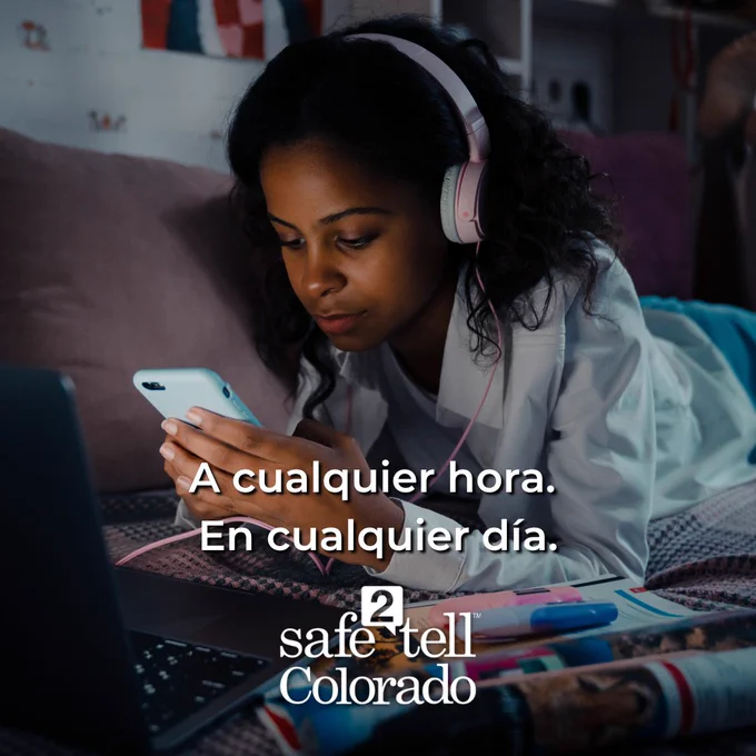 Persona usando auriculares con un smartphone y una laptop, con texto promocional visible para Safe2Tell Colorado.