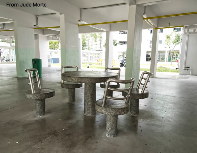 Stone table and stone chairs (with steel backrests) in the foreground of an apartment complex's ground floor in Singapore 🇸🇬 
These were likely built for senior citizens and caregivers as a place to rest or while away the time before going back to their respective units.