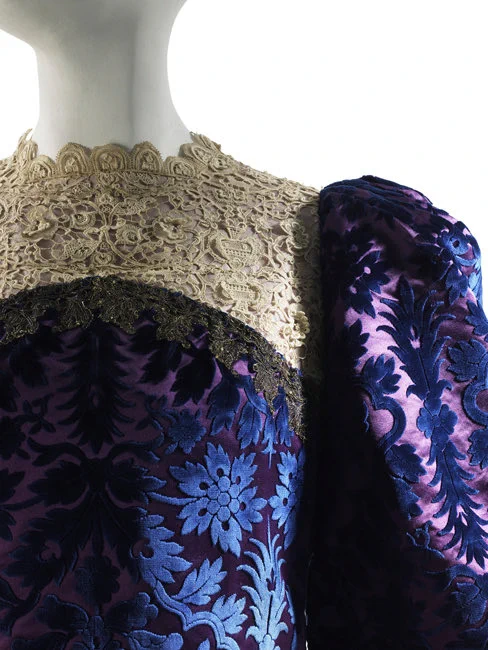 Detail of the purple voided velvet gown highlighting the voided velvet pattern and the square of lace around the neck
