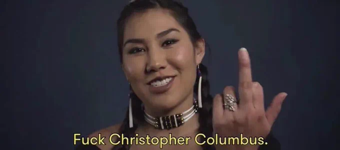 A native woman with her middle finger up and the caption “fuck Christopher Columbus”