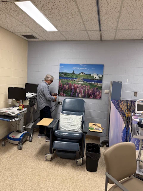 Dr Michael Weinberg of ArtWorks for Cancer installs a photographic work entitled Voglers Cove, Nova Scotia by Sherman Hines (rendered on metal by Posterjack) in the chemotherapy area at Orillia Soldiers' Memorial Hospital (OSMH).