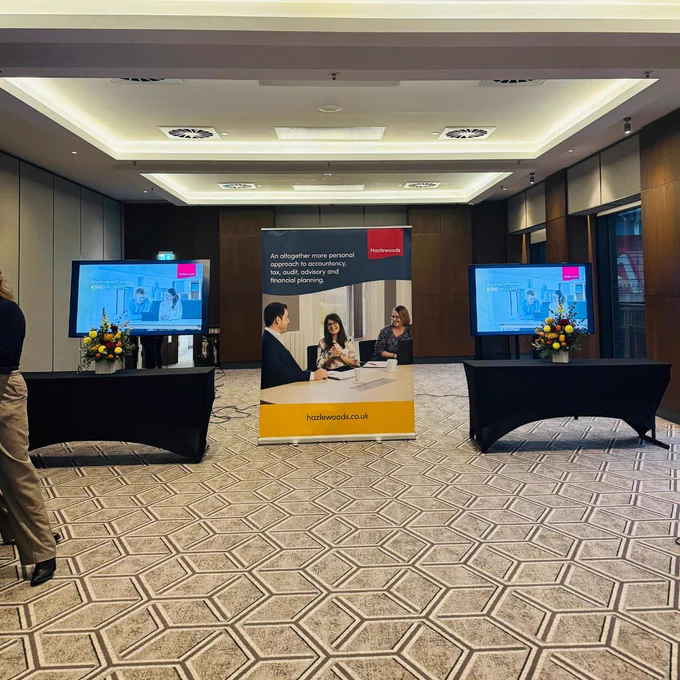 A Hazlewoods pop-up banner in between two tables with flowers on them. 