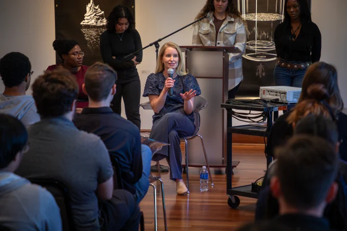 Speaker addressing an audience in a small, intimate conference setting.