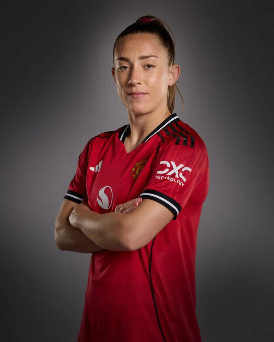 Maya Le Tissier poses for a photo, folding her arms, in our 2025/26 home shirt.