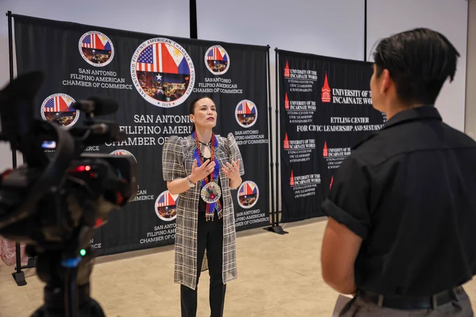 Mayor Jones speaks in front of a backdrop that reads “San Antonio Filipino American Chamber of Commerce” while interviewing on camera.