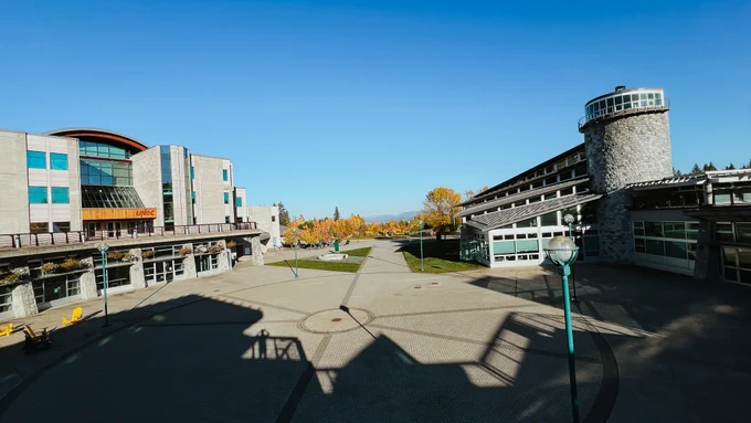 View of the University of Northern British Columbia campus looking out from the Agora Courtyard under a clear blue sky.