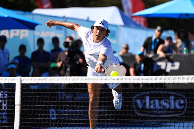  The image shows a man leaning forward to hit a pickleball shot with his right arm and left leg outstretched. He is wearing a white cap, white shirt, white shorts and white shoes. 

Courtesy of The Association of Pickleball Players.