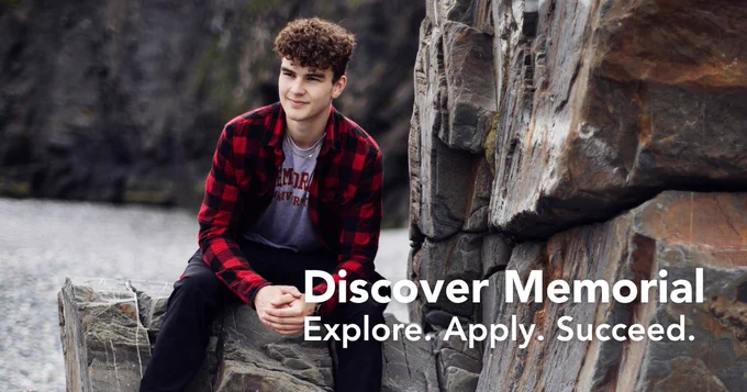 A student wearing a red and black plaid shirt and a Memorial University t-shirt sits on rocky cliffs near the coast, looking off to the side with a relaxed expression. The text on the image reads 'Discover Memorial. Explore. Apply. Succeed.'