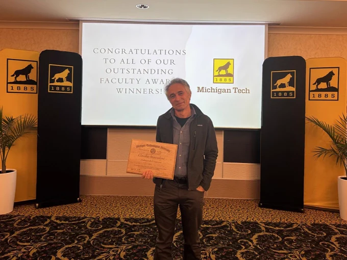 Professor Claudio Mazzoleni holding Distinguished Professor plaque  