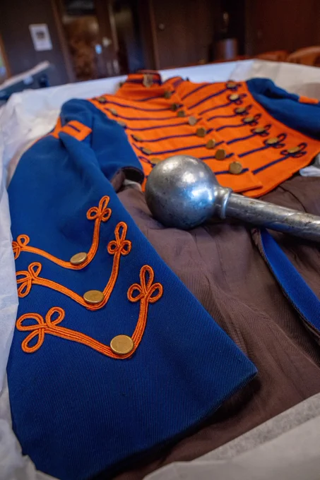 Blue and orange marching band uniform with gold accents and a silver mace.