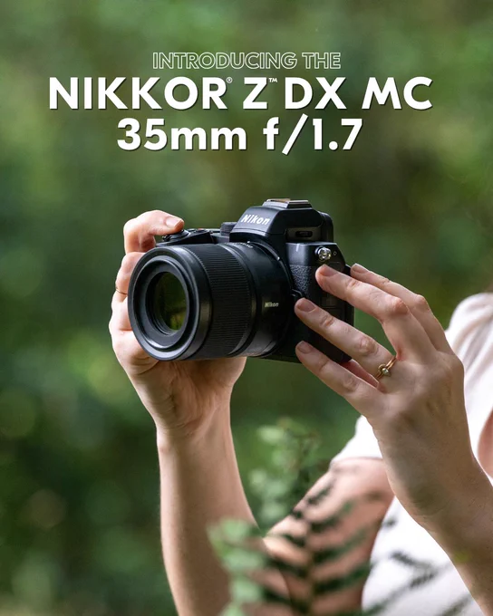 A photo of a person holding a Nikon camera with the NIKKOR Z DX MC 35mm f/1.7 lens attached, set against a blurred green outdoor background. Bold white text above reads: “Introducing the NIKKOR Z DX MC 35mm f/1.7.” 