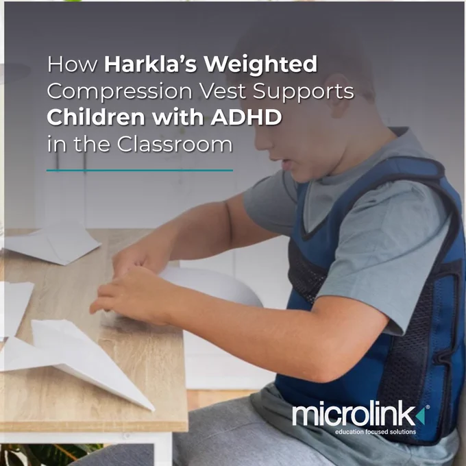 A young boy wearing a blue weighted compression vest sits at a classroom desk folding paper airplanes. Text on the image reads, “How Harkla’s Weighted Compression Vest Supports Children with ADHD in the Classroom.” The Microlink logo appears in the bottom right corner.