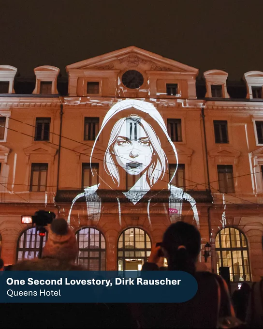 A female character included as part of One Second Lovestory projected on to a large building. She is illustrated in white and in the foreground of the image are two visitors watching the projection and taking photos of it.